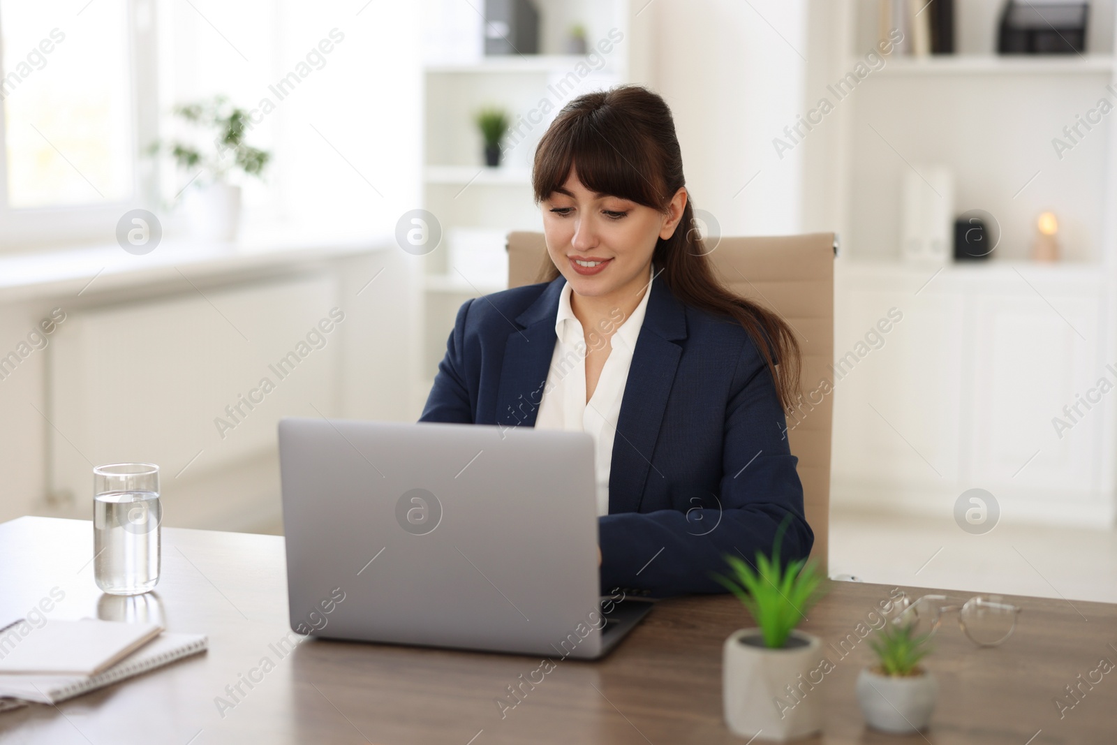 Photo of Woman watching webinar at wooden table in office