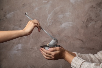 Photo of Volunteer putting food into bowl of poor woman on color background, closeup. Concept of help