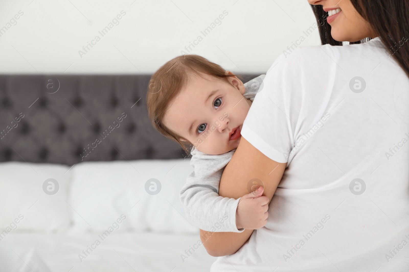 Photo of Mother holding her adorable baby in bedroom. Space for text