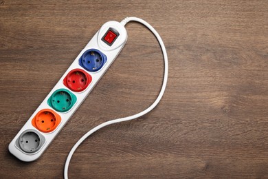 Power strip with extension cord on wooden floor, top view. Space for text