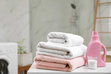 Photo of Clean towels and detergents on table in laundry room