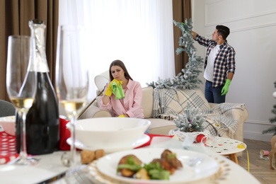 Photo of Couple cleaning messy room after New Year party