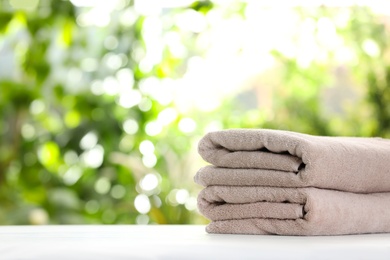 Stack of clean soft towels on table against blurred background. Space for text