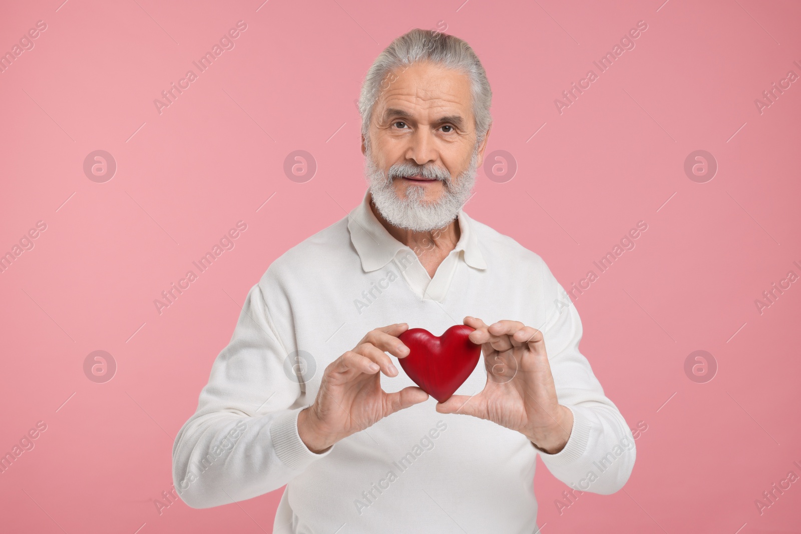 Photo of Senior man with red decorative heart on pink background