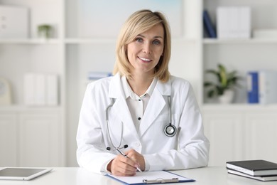 Photo of Portrait of smiling doctor at table in office