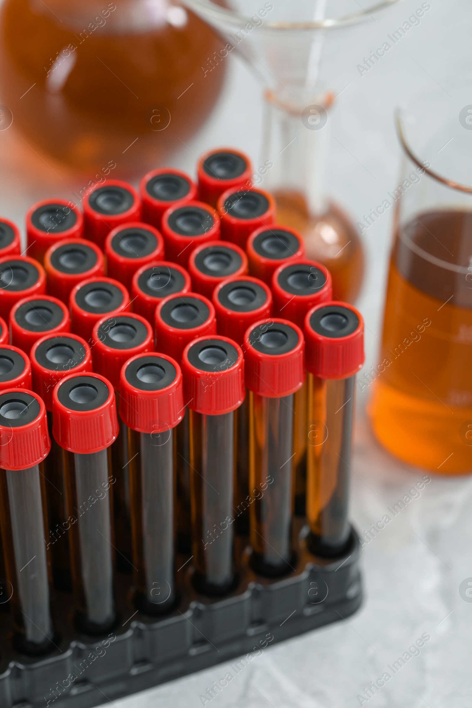 Photo of Test tubes with brown liquid in stand on table, closeup