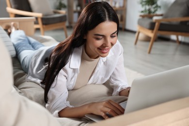 Photo of Young woman working with laptop on sofa at home
