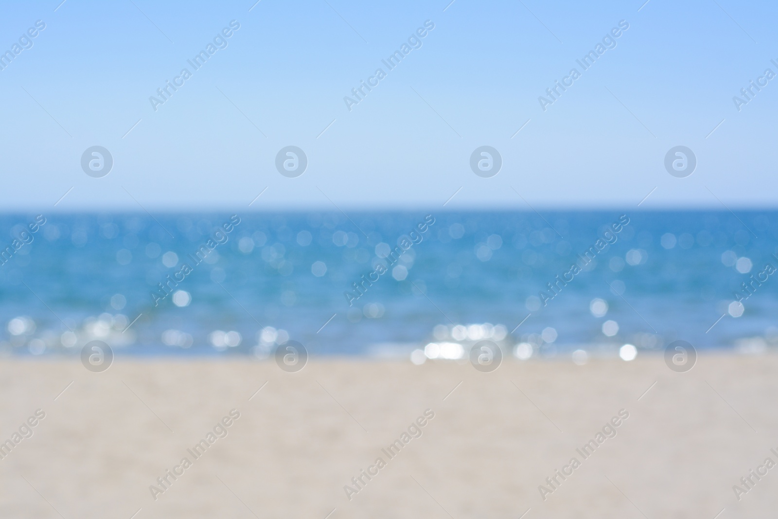 Photo of Sandy beach near sea on sunny day, blurred view