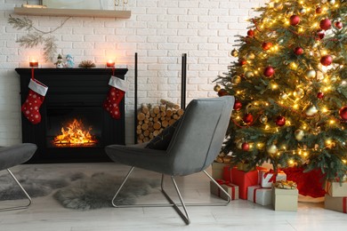 Photo of Beautiful Christmas tree near fireplace and cosy armchair in room. Interior design