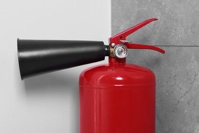 Photo of Red fire extinguisher in corner, closeup view