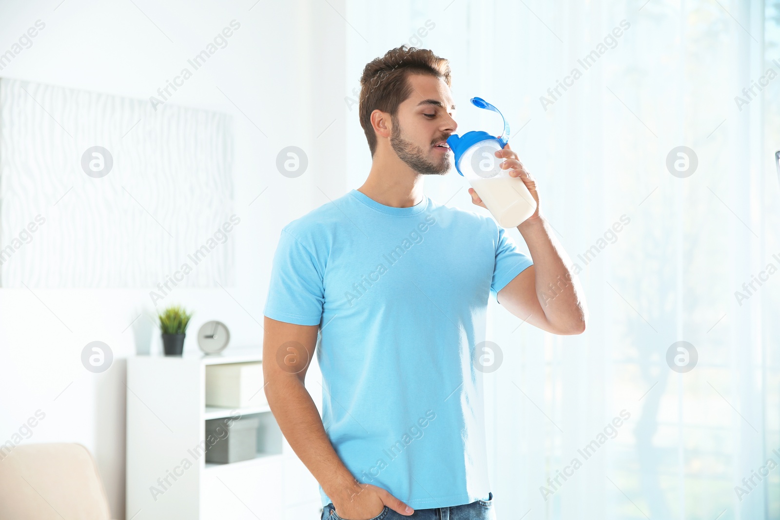 Photo of Young man with bottle of protein shake at home