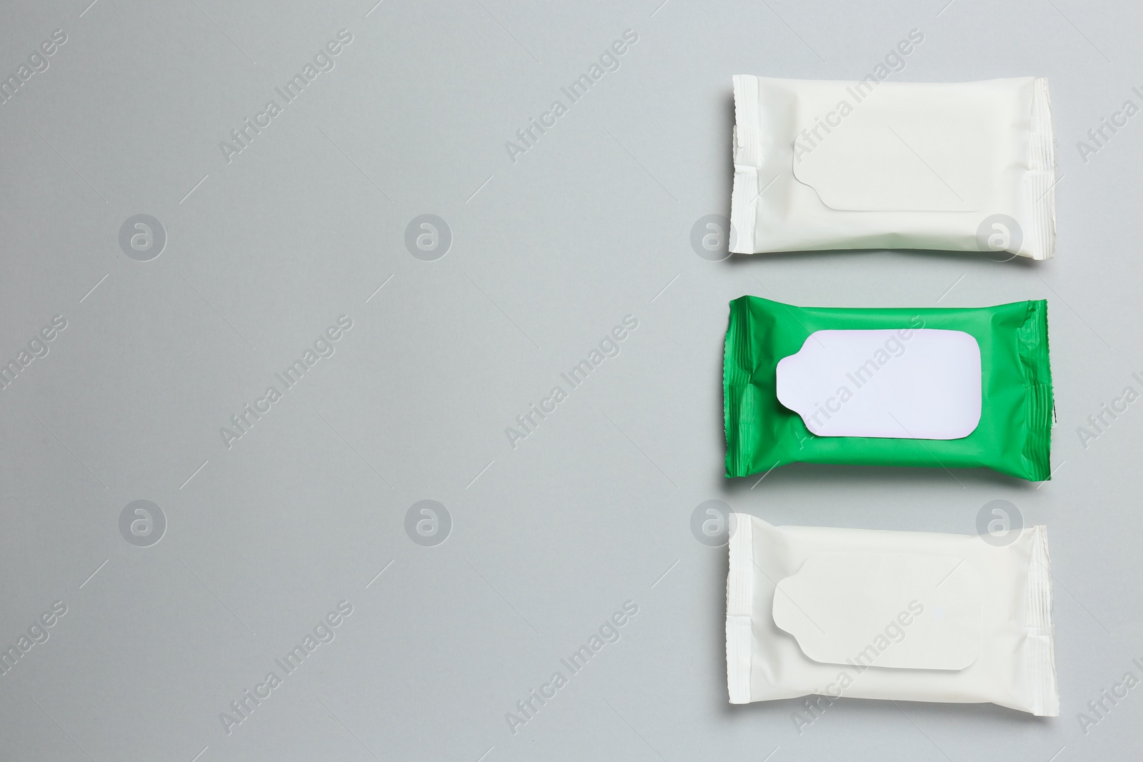 Photo of Wet wipes flow packs on light grey background, flat lay. Space for text