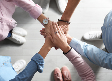 Photo of People holding hands together over light background, top view. Unity concept