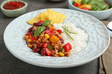 Tasty chili con carne served with rice on gray table
