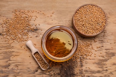 Photo of Natural oil and mustard seeds on wooden table, flat lay