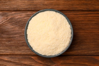 Photo of Delicious grated parmesan cheese in bowl on wooden table, top view