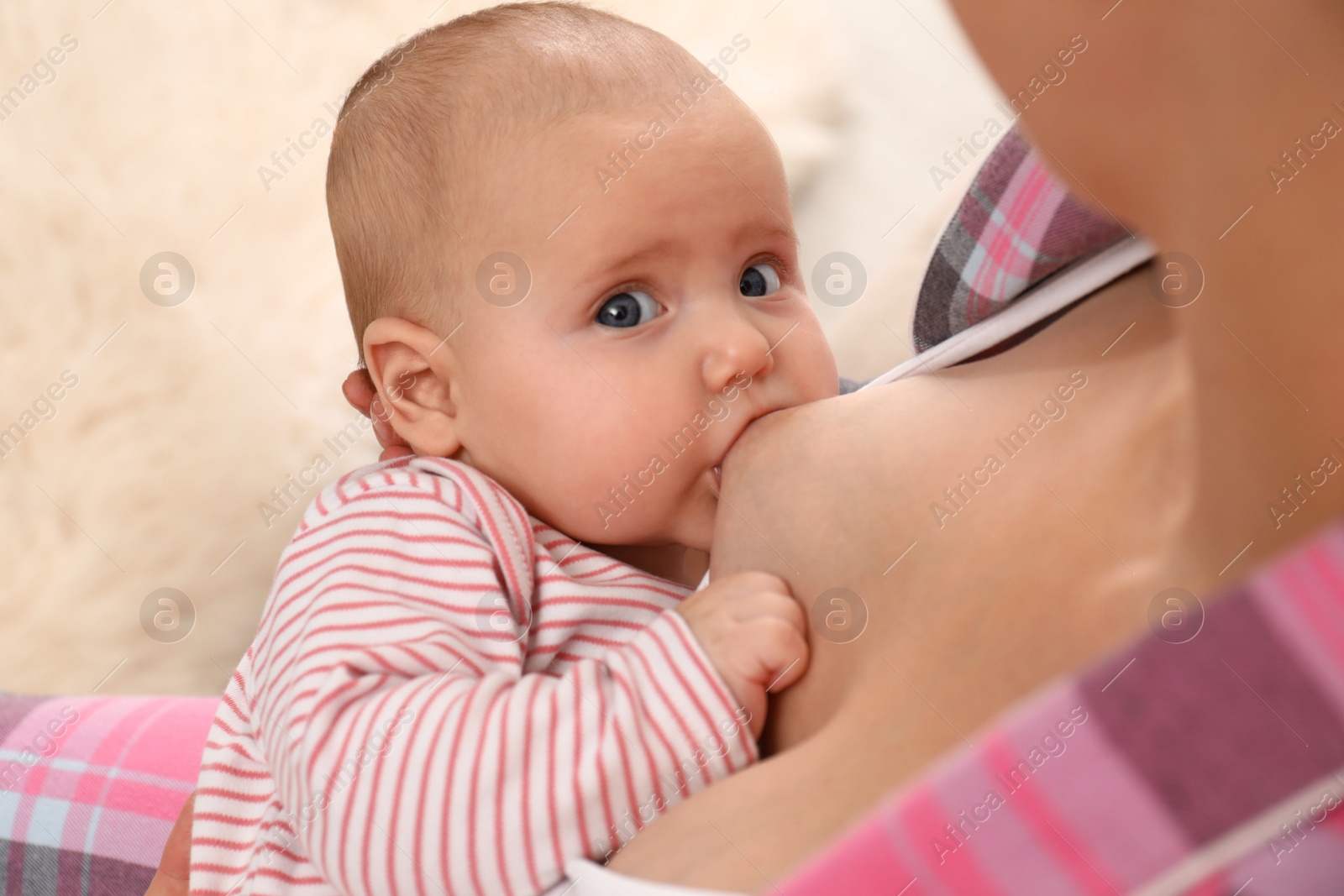 Photo of Young woman breastfeeding her little baby at home, closeup