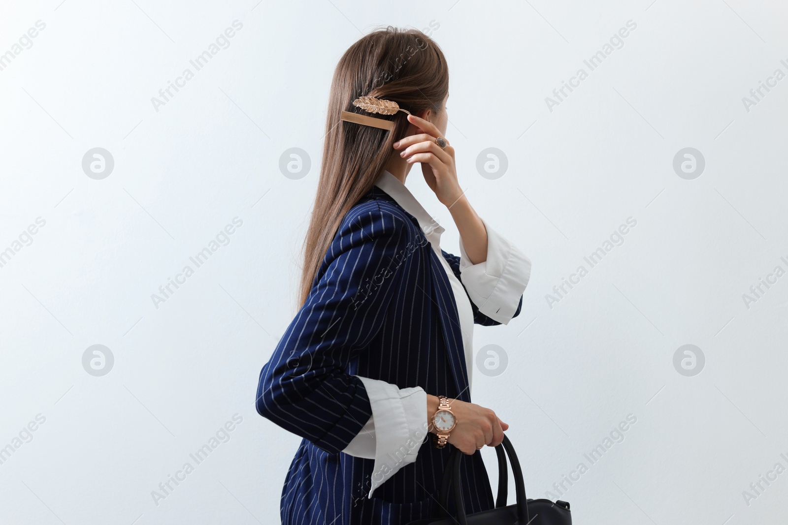 Photo of Young woman with beautiful hair clips on light background, back view