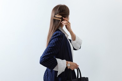 Photo of Young woman with beautiful hair clips on light background, back view