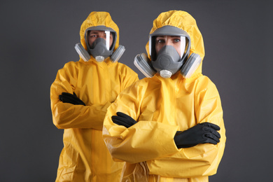 Photo of Man and woman wearing chemical protective suits on grey background. Virus research