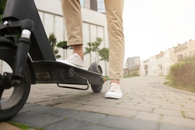 Photo of Man with modern kick scooter on city street, closeup. Space for text