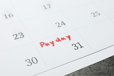 Photo of Calendar page with marked payday date on table, closeup