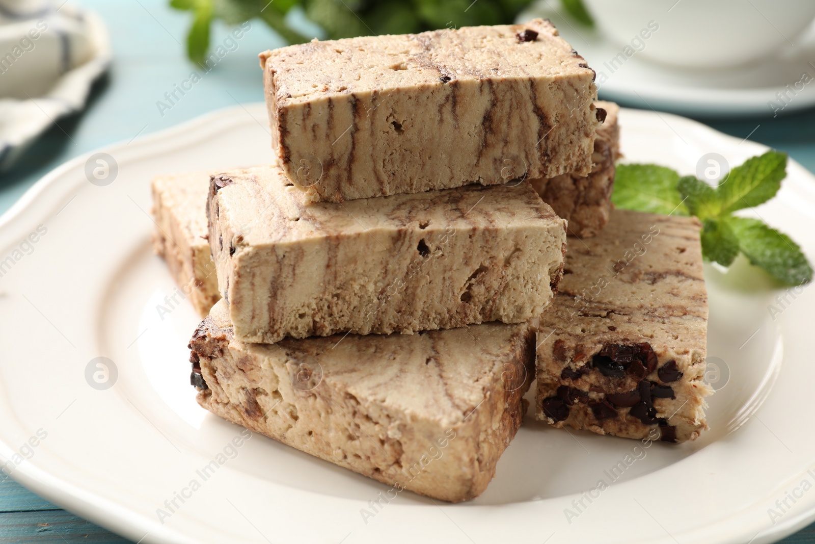 Photo of Pieces of tasty chocolate halva and mint on table, closeup