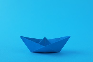 Photo of Handmade paper boat on light blue background. Origami art