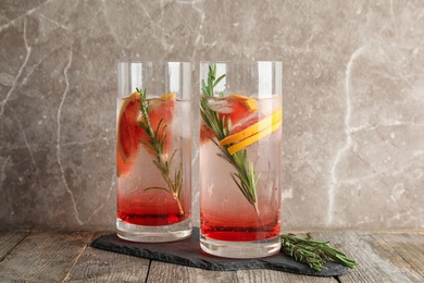 Glasses of refreshing grapefruit cocktail with rosemary on table