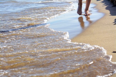 Photo of Woman walking on sandy beach near sea, closeup. Space for text
