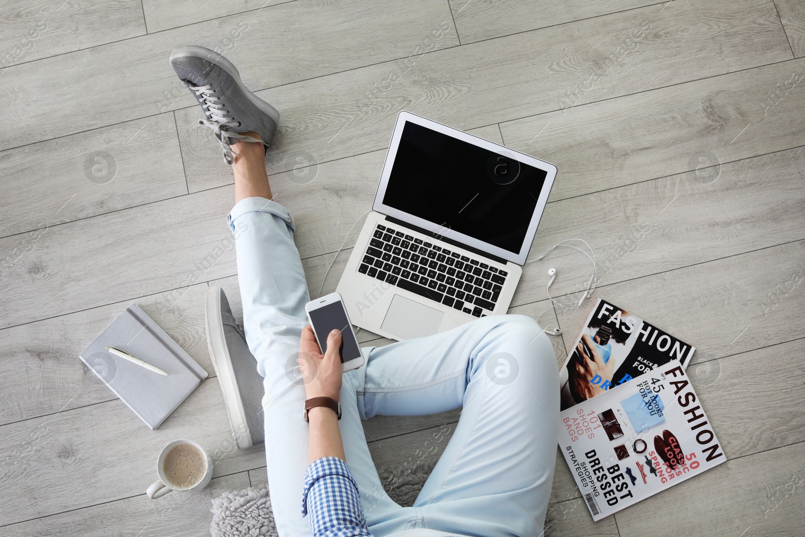 Photo of Young man with laptop and mobile phone sitting on floor, top view