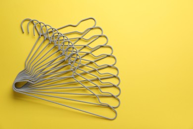 Photo of Empty hangers on yellow background, top view. Space for text