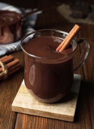 Photo of Cup of delicious hot chocolate with cinnamon stick on wooden table