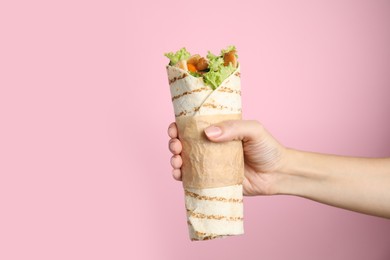 Woman holding delicious chicken shawarma on pink background, closeup