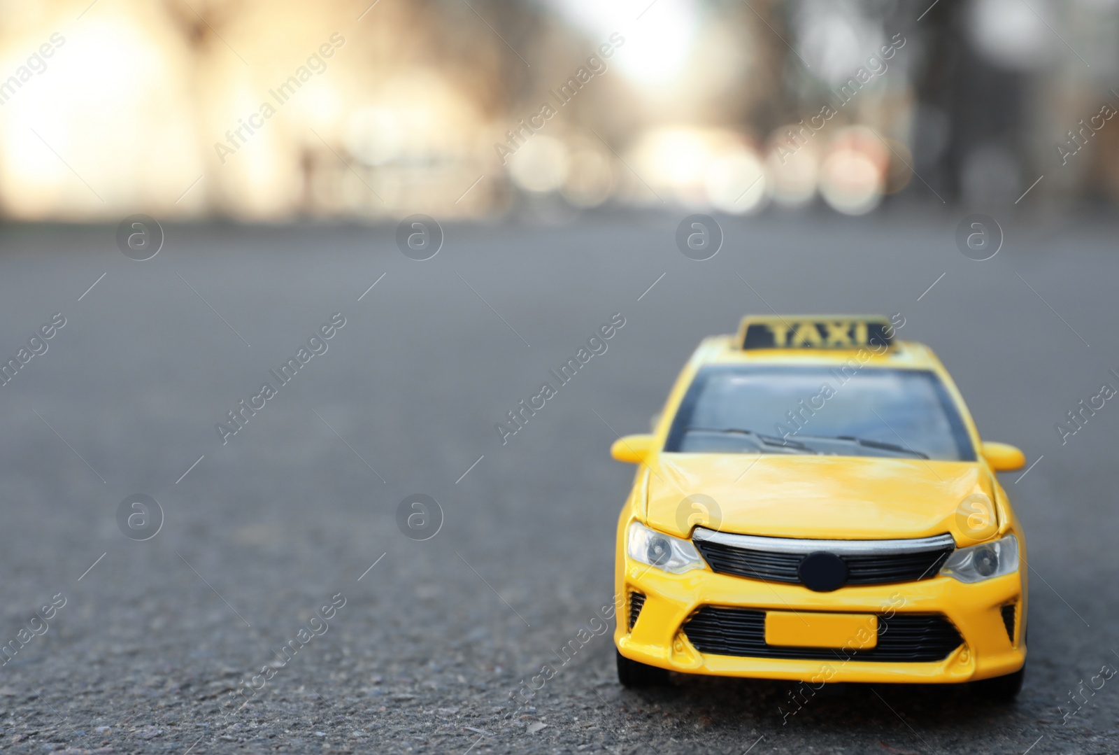 Photo of Yellow taxi car model on city street. Space for text