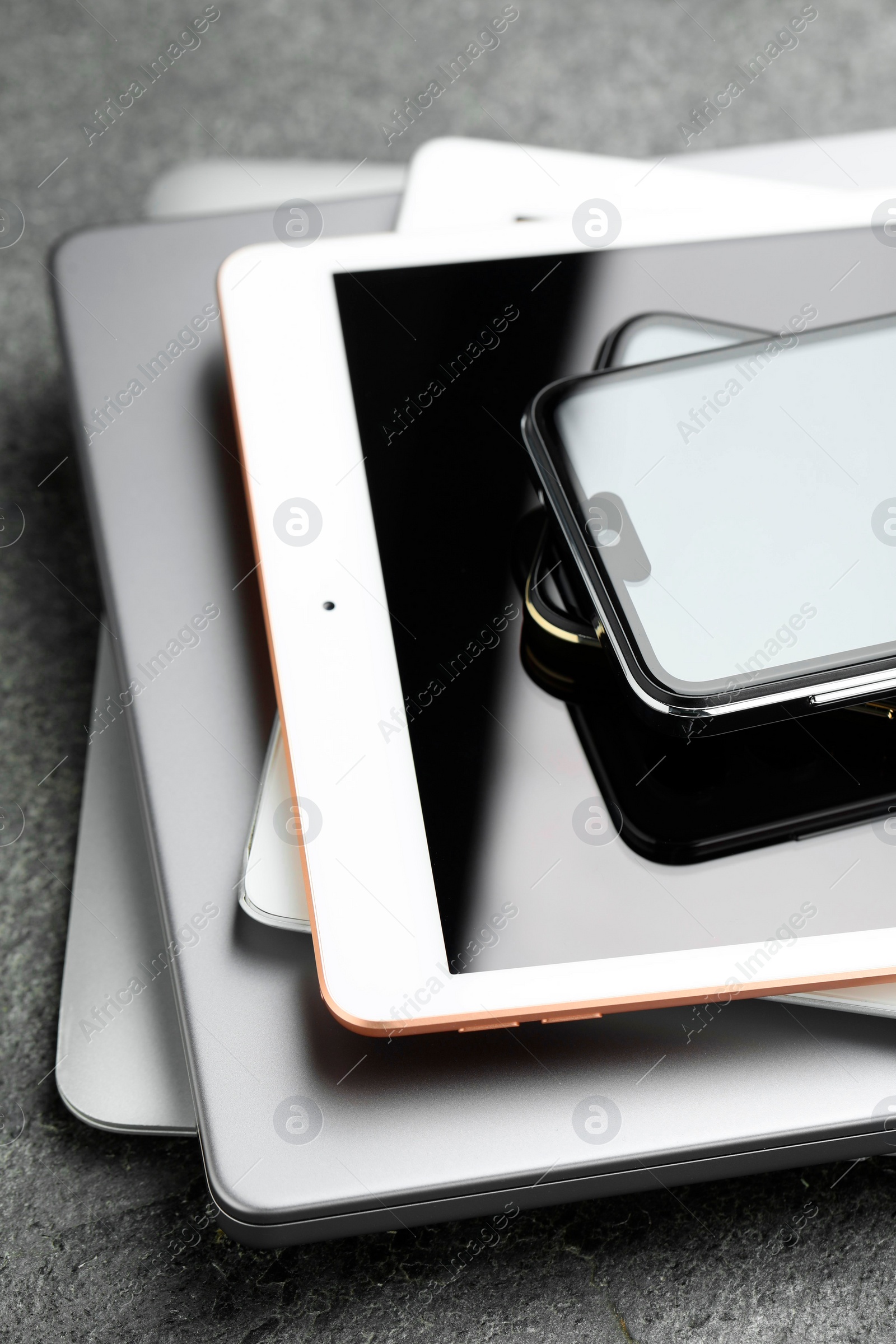 Photo of Stack of electronic devices on grey table, closeup