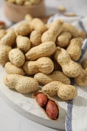 Photo of Fresh unpeeled peanuts on white table, closeup