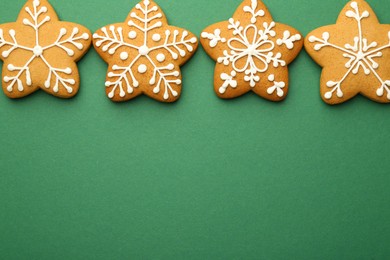 Photo of Tasty Christmas cookies with icing on green background, flat lay. Space for text