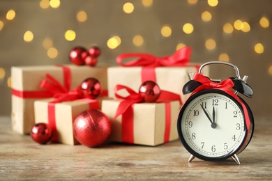 Photo of Vintage alarm clock with decor on wooden table against blurred Christmas lights. New Year countdown
