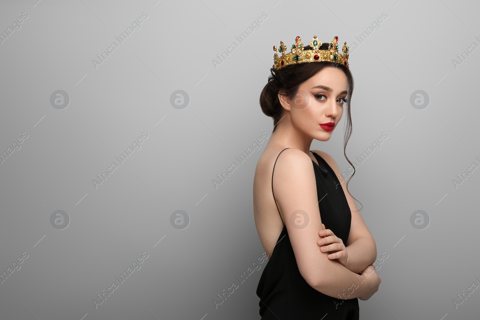 Photo of Beautiful young woman wearing luxurious crown on light grey background, space for text