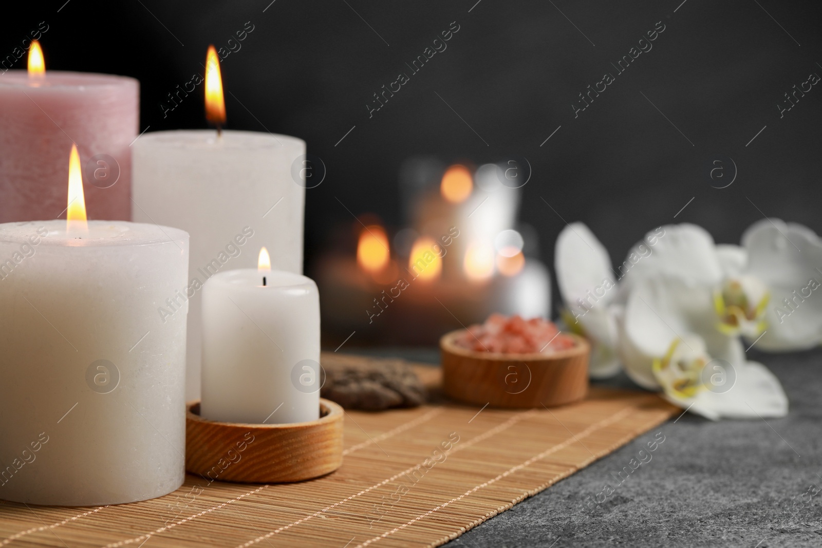 Photo of Beautiful spa composition with burning candles on dark grey table. Space for text