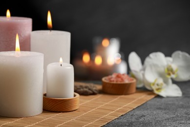 Photo of Beautiful spa composition with burning candles on dark grey table. Space for text