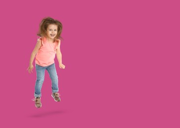 Cute girl jumping on dark pink background, space for text