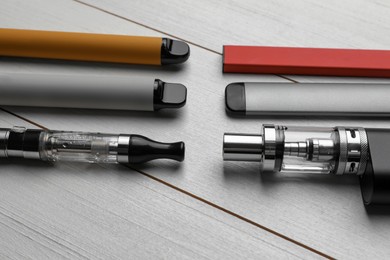 Different electronic cigarettes on white wooden table