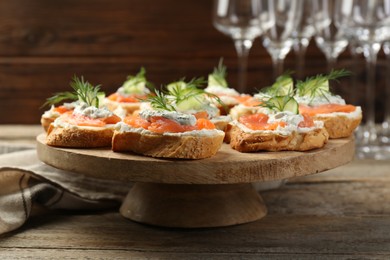 Tasty canapes with salmon, cucumber, cream cheese and dill on wooden table