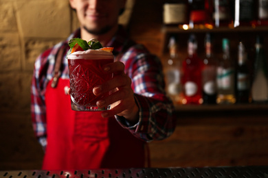 Photo of Bartender preparing fresh alcoholic cocktail in bar, focus on hand. Space for text