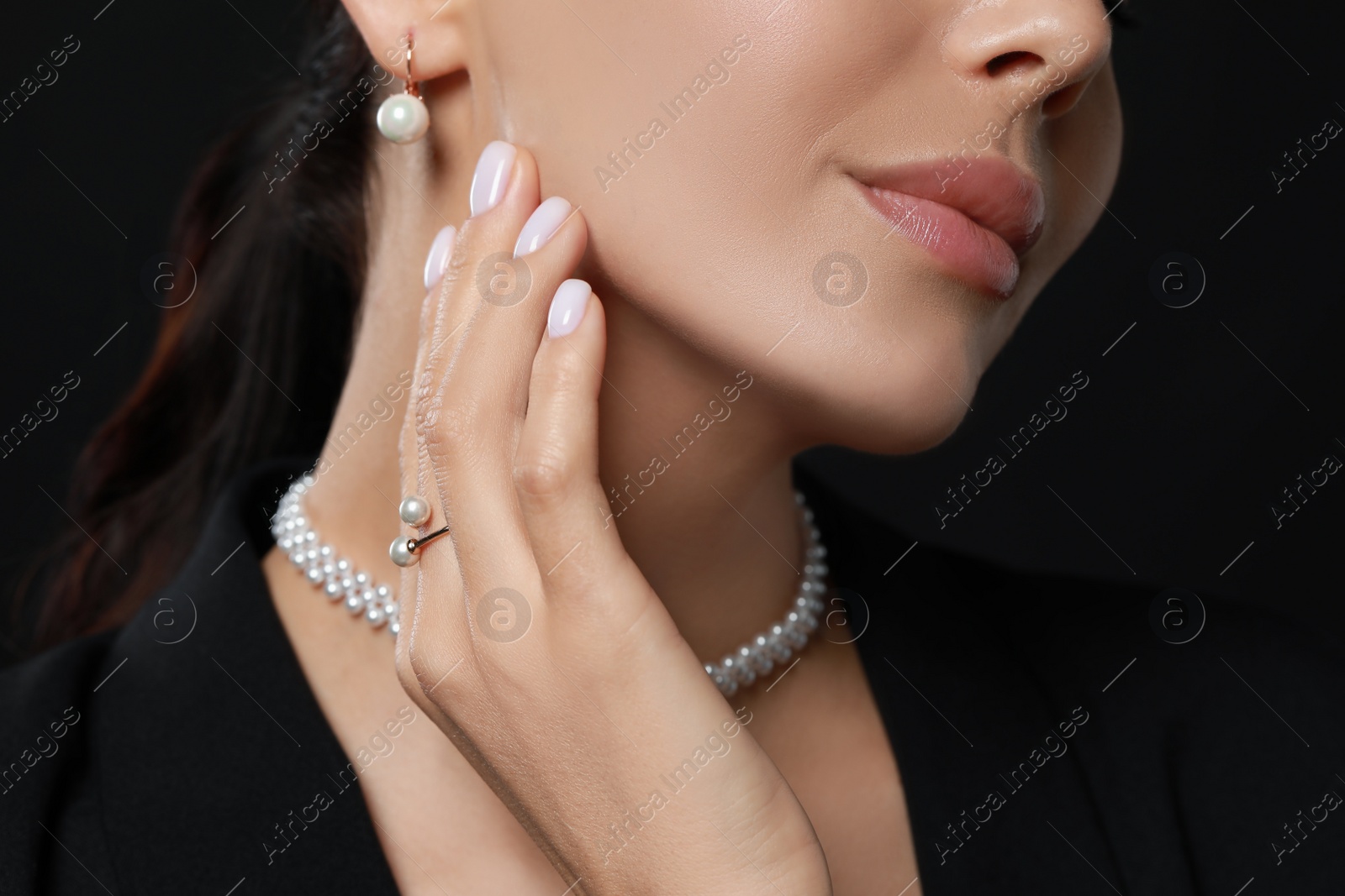 Photo of Young woman with elegant pearl jewelry on black background, closeup