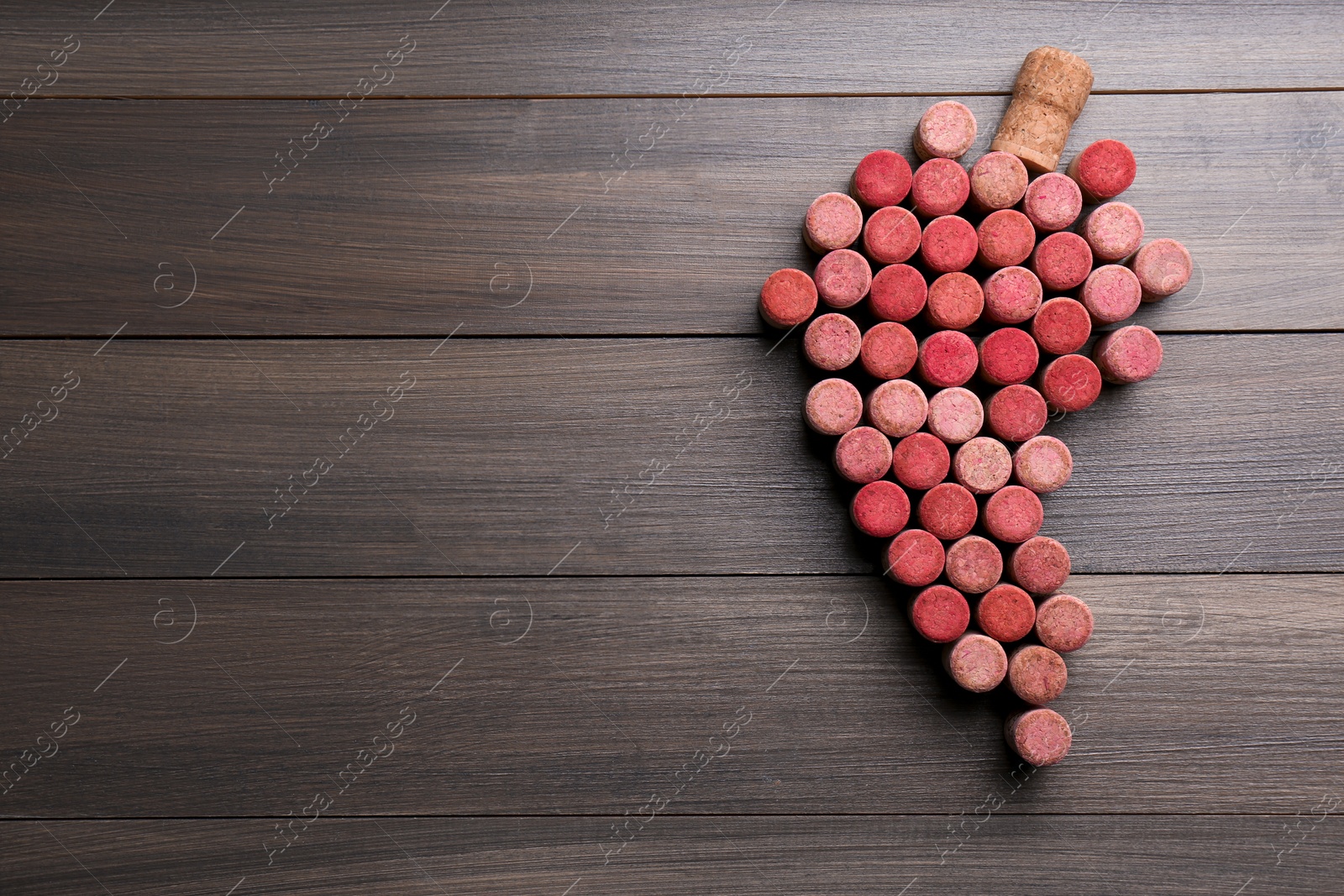 Photo of Grape made of wine bottle corks on wooden table, top view. Space for text