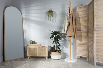 Photo of Stylish hallway room interior with wooden commode, coat rack and large mirror