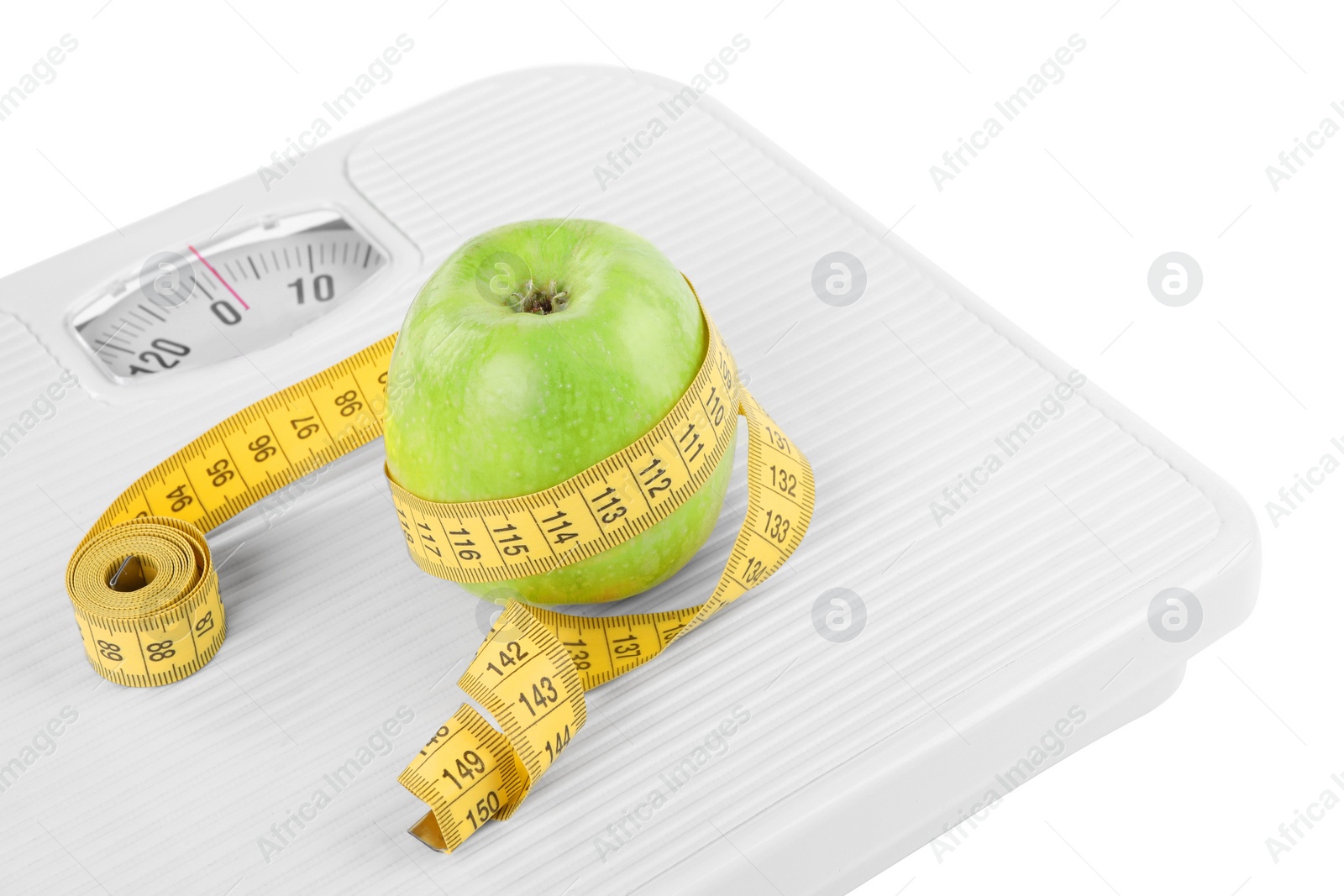 Photo of Weight loss concept. Ripe apple and measuring tape on scales against white background